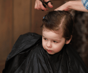Coiffeuse du Salon de Sandie en train de coiffer un enfant avec douceur